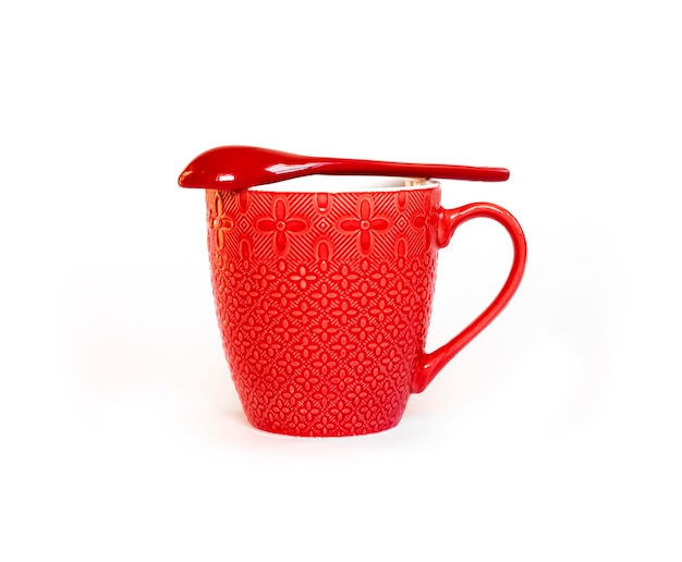 Tasse en céramique rouge avec une cuillère en céramique rouge allongée dessus