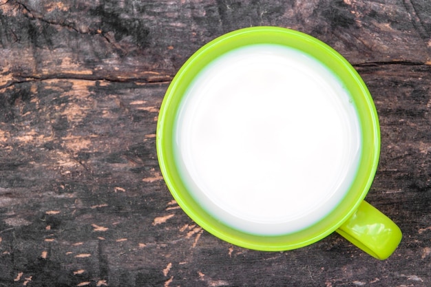 La tasse en céramique verte avec du lait biologique est une vieille table en bois