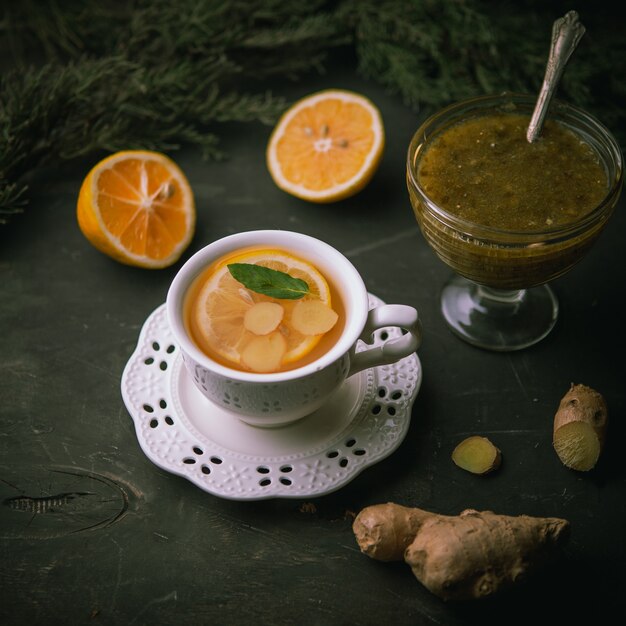 Tasse chaude de thé vert au citron, gingembre, confiture sur surface noire, vue du dessus