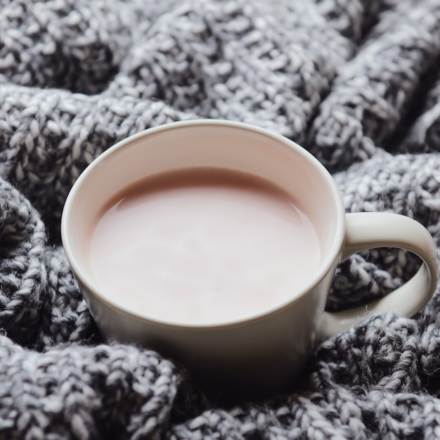 Une tasse de chocolat chaud au lait sur un plaid en laine grise. Confort de la maison. Vue de dessus