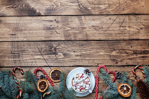 Une tasse de chocolat chaud avec des guimauves. Arbre de Noël et décorations, caramel de canne et noix d'oranges Espace de copie de fond en bois.