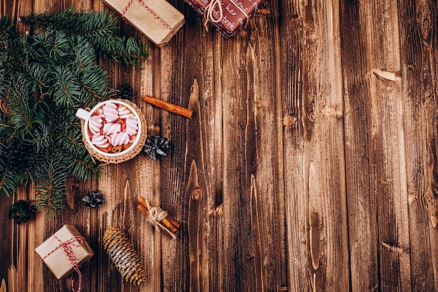 Tasse de chocolat chaud avec guimauves, cannelle, cônes et branches de sapin sur la table en bois