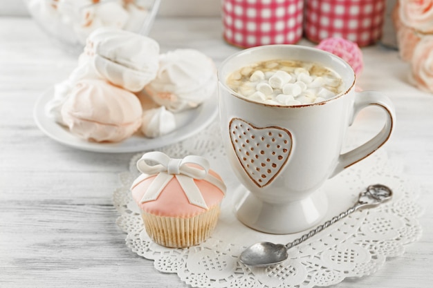 Tasse de chocolat chaud avec des guimauves, sur fond de bois clair