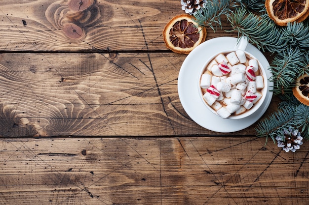 Tasse de chocolat chaud avec des guimauves, des oranges séchées et des branches