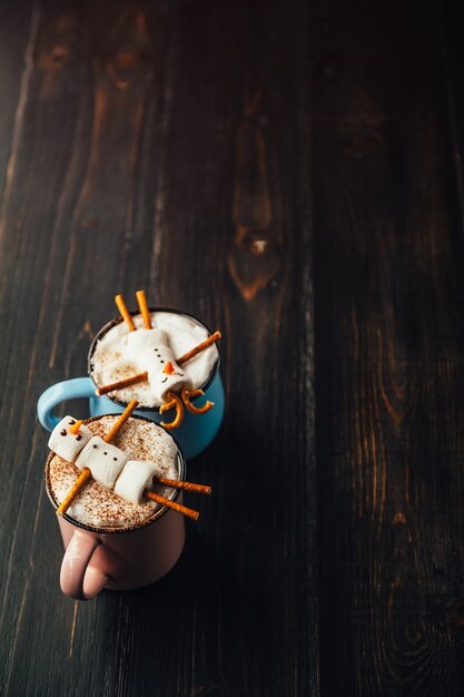 Une tasse de chocolat chaud sur une table en bois avec un homme à la guimauve qui se repose dans une tasse