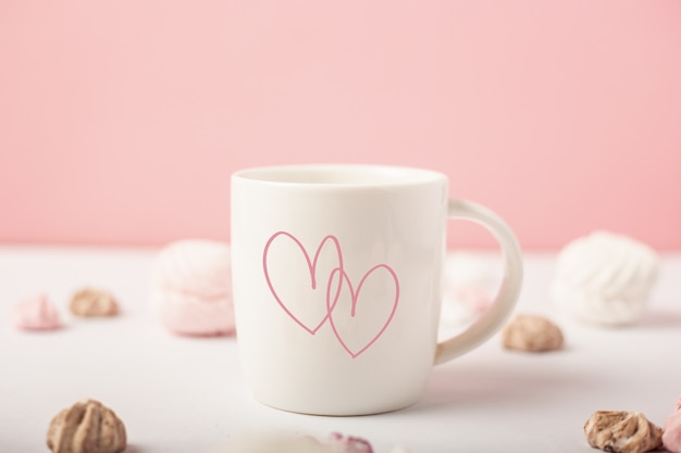 Tasse avec coeurs et bonbons sur fond rose. Concept de la Saint-Valentin. Bannière.