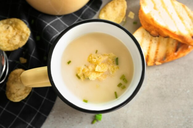 Tasse de délicieuse soupe de pommes de terre avec des chips sur la table