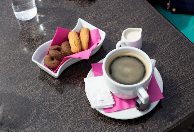 Tasse avec de délicieux biscuits au café chaud et du lait sur la table en gros plan