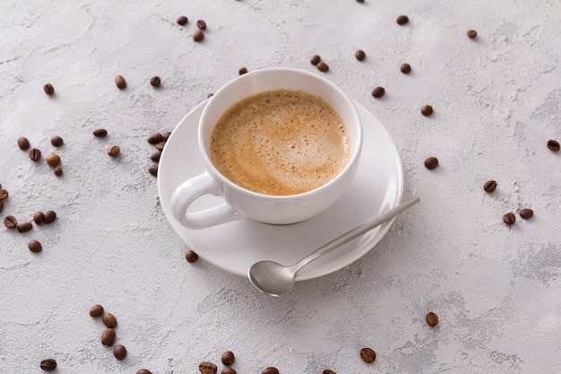 Une tasse de délicieux cappuccino chaud et de haricots sur une table en béton gris