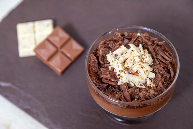 Tasse de dessert avec mousse au chocolat au lait et copeaux de chocolat blanc