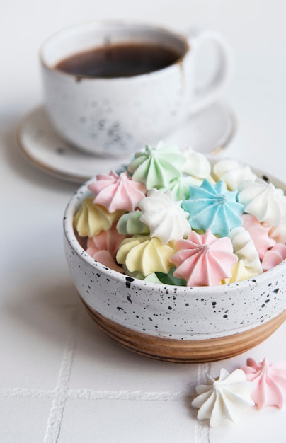 Tasse avec du café et de petites meringues dans le bol sur un fond carrelé