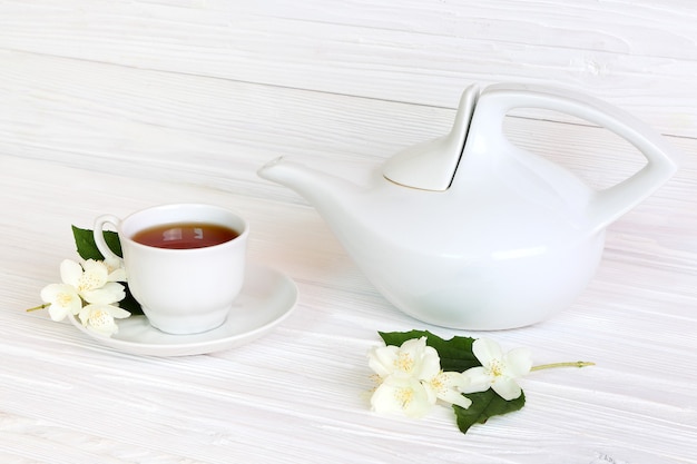 Photo tasse avec du thé au jasmin et des fleurs de jasmin sur un fond en bois clair