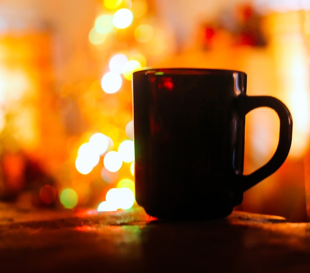 Une tasse avec du thé chaud sur des décorations de Noël colorées se bouchent.