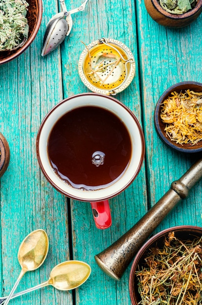 Tasse avec du thé utile à partir d'herbes médicinales sur un fond en bois.Divers ingrédients de tisane