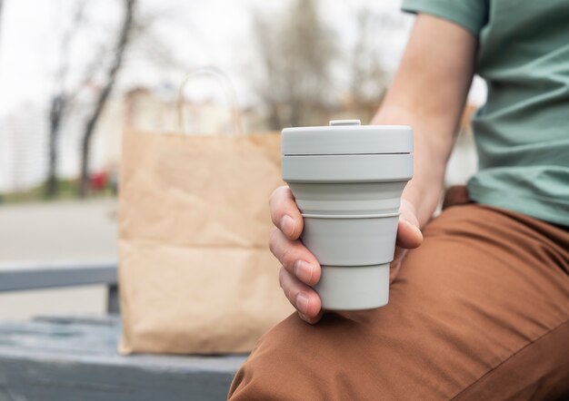 Tasse écologique pliable pour le café ou le thé à emporter. Main masculine avec tasse en silicone durable. Mode de vie zéro déchet.