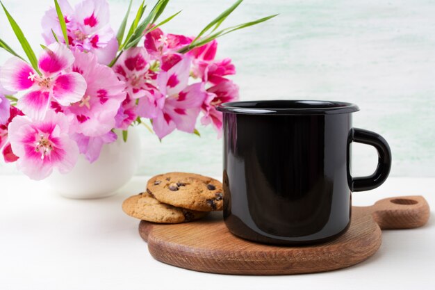 Tasse en émail noir avec des fleurs de clarkia rose