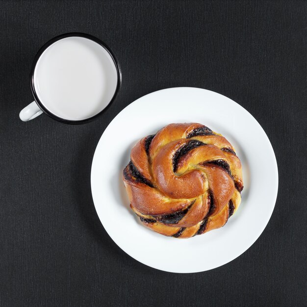 Tasse émaillée de lait et pain avec crème au chocolat sur fond noir en pierre