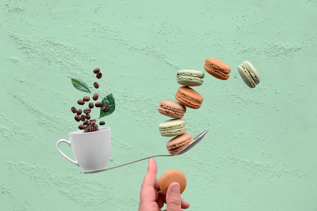 Tasse d'équilibrage de café et macaronos sur un doigt