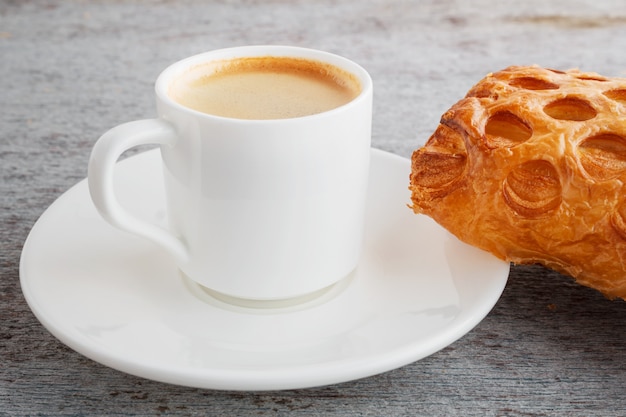 tasse d&#39;espresso fraîchement préparé et un croissant sur un dos en bois