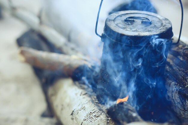 tasse en fer avec du thé chaud lors d'un voyage de camping mode de vie actif parc jaune d'automne