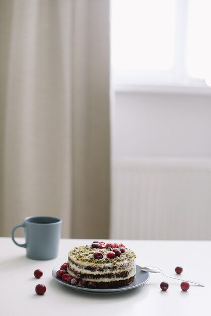 Tasse et gâteau décoré de baies sur tableau blanc