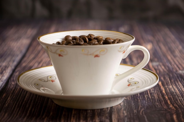 Une tasse avec des grains de café sur un fond sombre