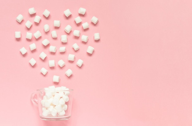 Tasse avec guimauve blanche et bonbons en forme de coeur sur fond rose