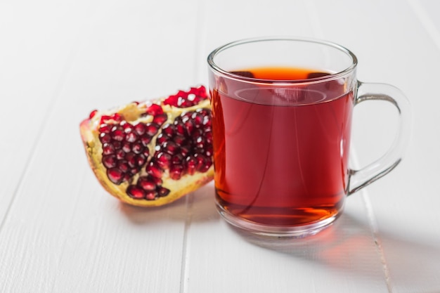 Une tasse de jus de grenade et une grenade mûre sur un tableau blanc. Boisson utile pour la santé.