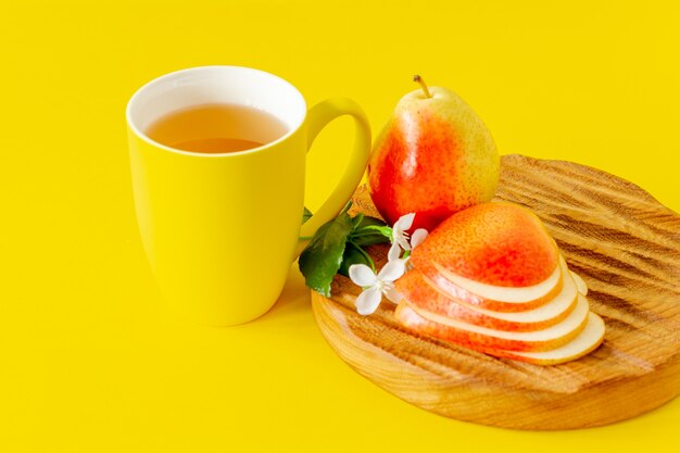 Tasse de jus de poire et poires mûres sur planche à découper en bois et fond jaune avec espace de copie.