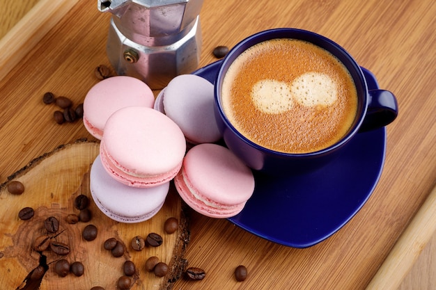 Photo tasse de macarons au café et grains de café sur un plateau et cafetière geyser sur un plateau en bois