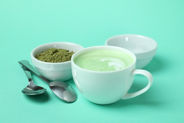 Tasse de matcha latte et accessoires pour faire sur fond menthe