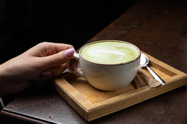 Une tasse de matcha latte avec une cuillère sur un plateau en bois