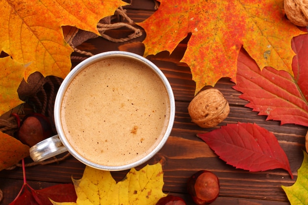 Tasse en métal avec cappuccino, noix et feuilles d'automne