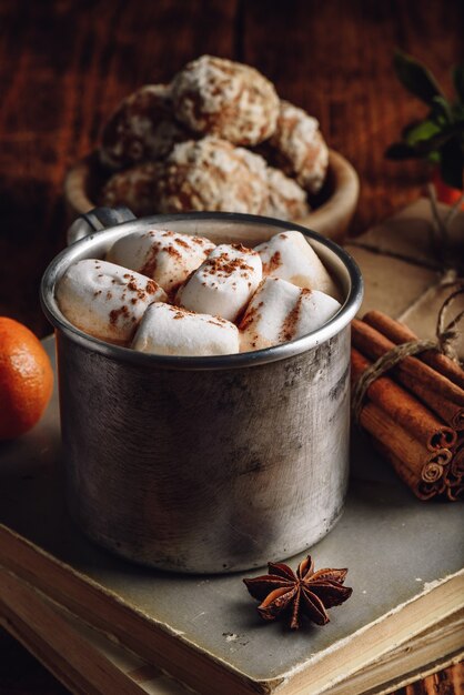 Tasse en métal de chocolat chaud avec des guimauves dans un cadre rustique