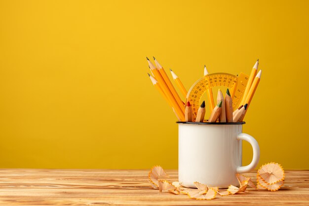 Tasse en métal avec des crayons pointus et des copeaux de crayon sur un bureau en bois