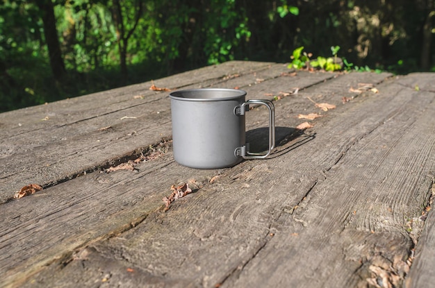 Tasse en métal gris dans la nature sur une table en bois