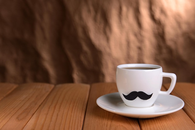 Tasse avec moustache sur table sur fond marron