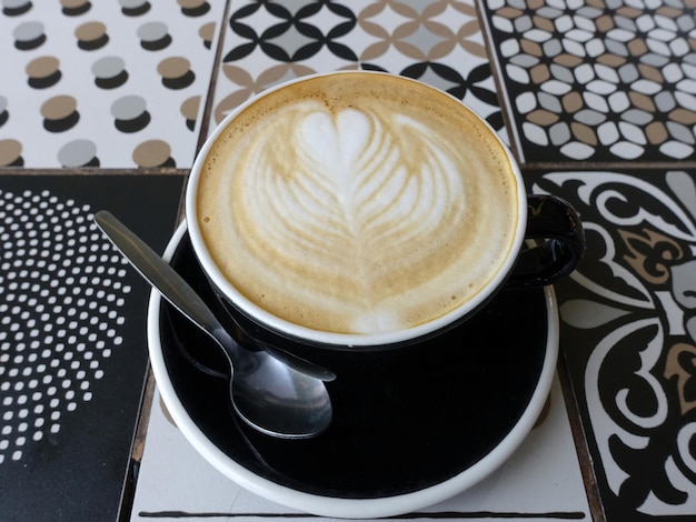 Tasse noire de café avec une cuillère à café sur la table