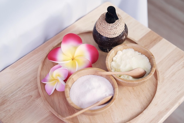 Tasse de noix de coco avec du sel pour le traitement d'exfoliation dans un bol en bois et des fleurs de Plumeria dans un spa thaïlandais