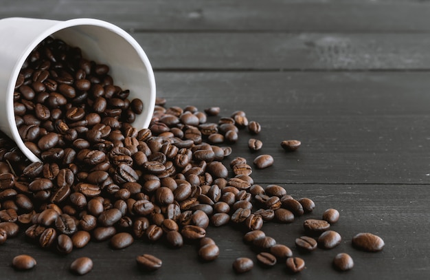 Tasse de papier blanc et grains de café sur vieux bois