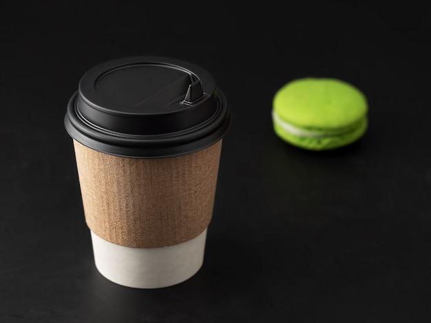 Tasse en papier avec une boisson chaude, du café ou du thé. Près des macarons. Fermer.