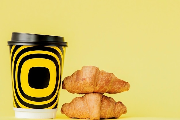 Tasse en papier de café et croissants sur fond jaune Espace de copie