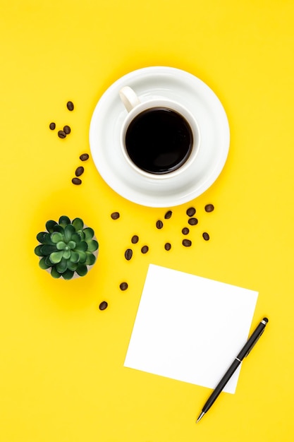 Tasse de papier à café et de grains de café sur fond jaune à plat