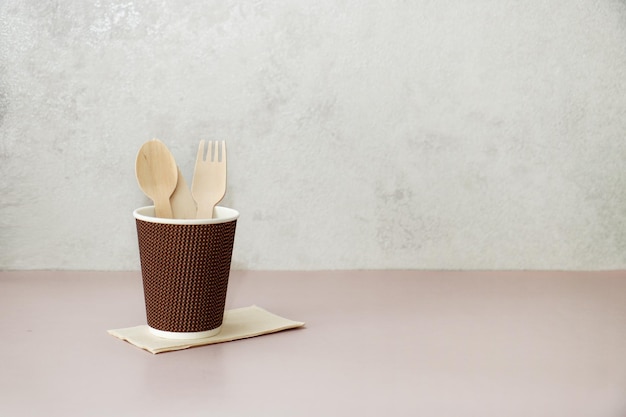 une tasse de papier avec des couverts jetables et une serviette sur la table