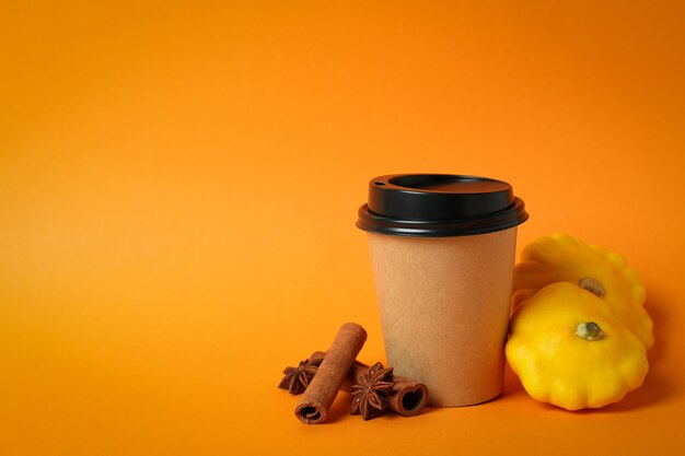 Tasse en papier et ingrédients pour le latte de citrouille sur fond orange