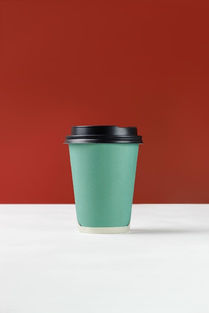 Tasse en papier vert avec café sur fond blanc et mur rouge Maquette de texte de tasse en papier jetable