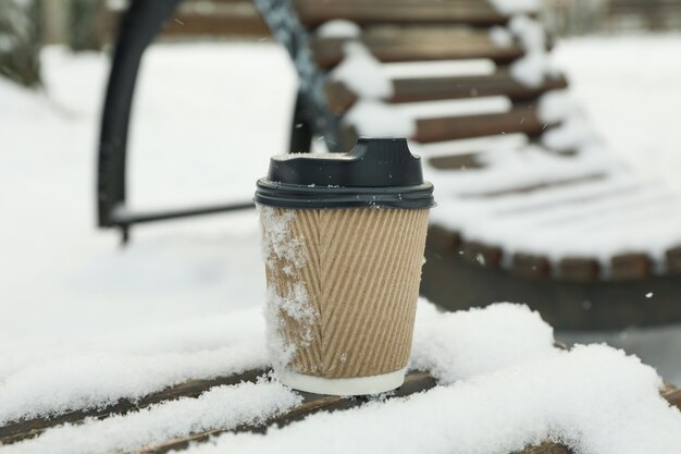 Tasse de papier vierge sur un banc en plein air en hiver