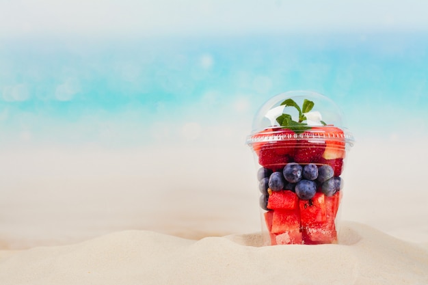 Tasse en plastique pleine de fruits coupés et baies