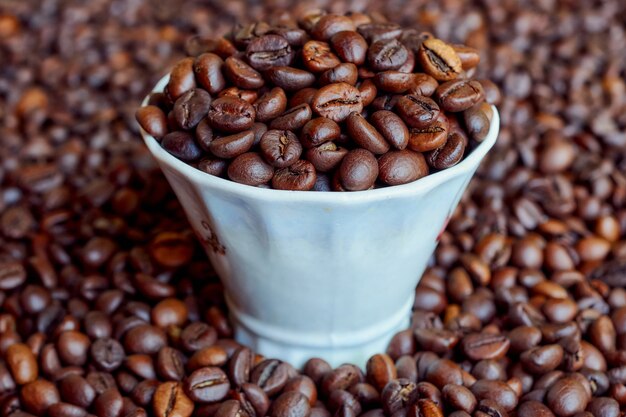 Une tasse pleine de grains de café fraîchement torréfiés.