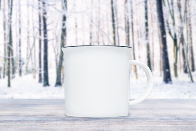 Tasse en porcelaine dans la neige en journée d'hiver sur planche de bois